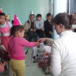 Maggie passing out birthday presents to her primary class kids